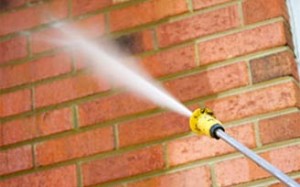 Professional cleaning the brick exterior of a commercial facility with a pressure washer